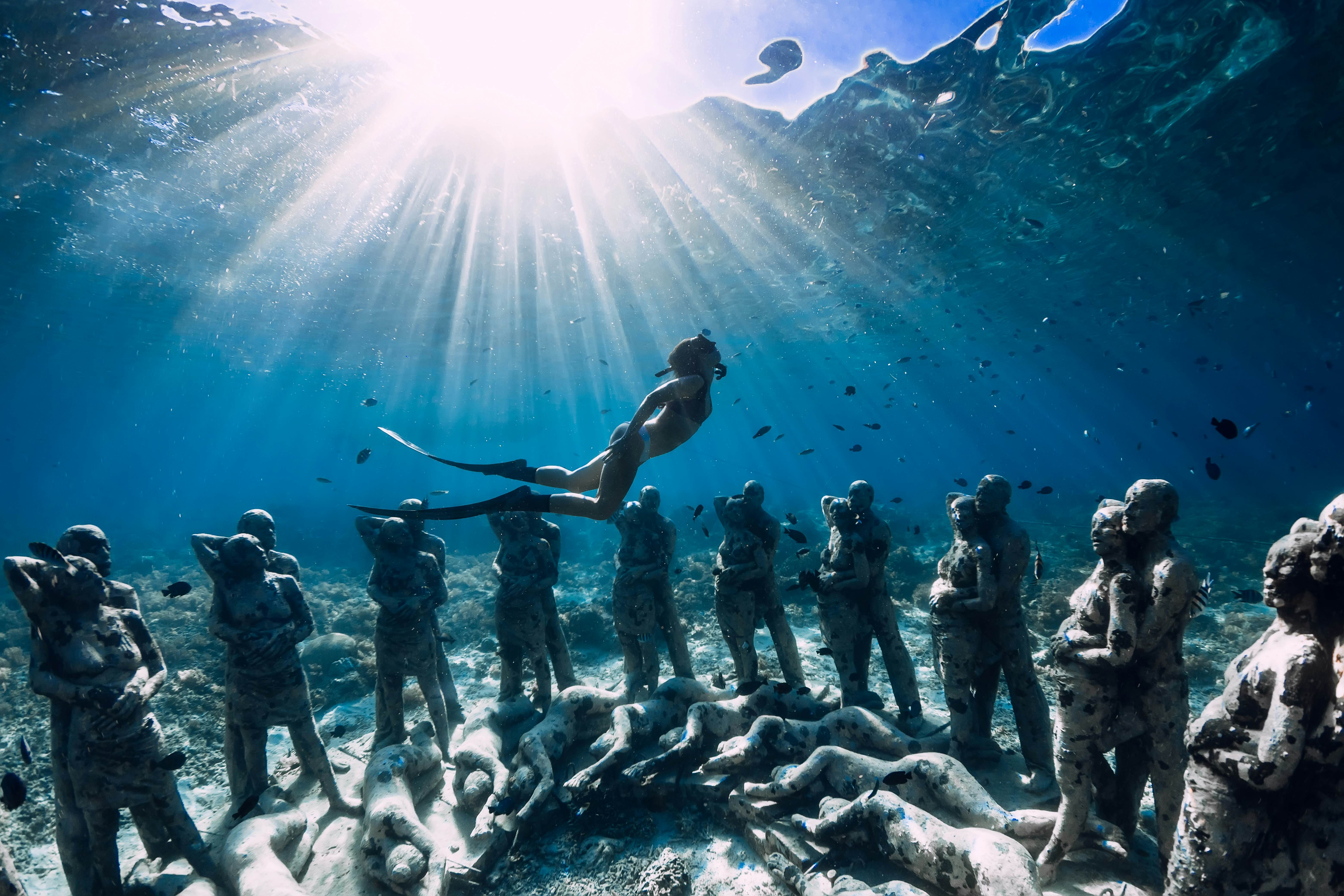 May 12, 2019. Gili Meno, Indonesia. Woman freediver with fins dive near underwater statues. Underwater tourism in the ocean.
